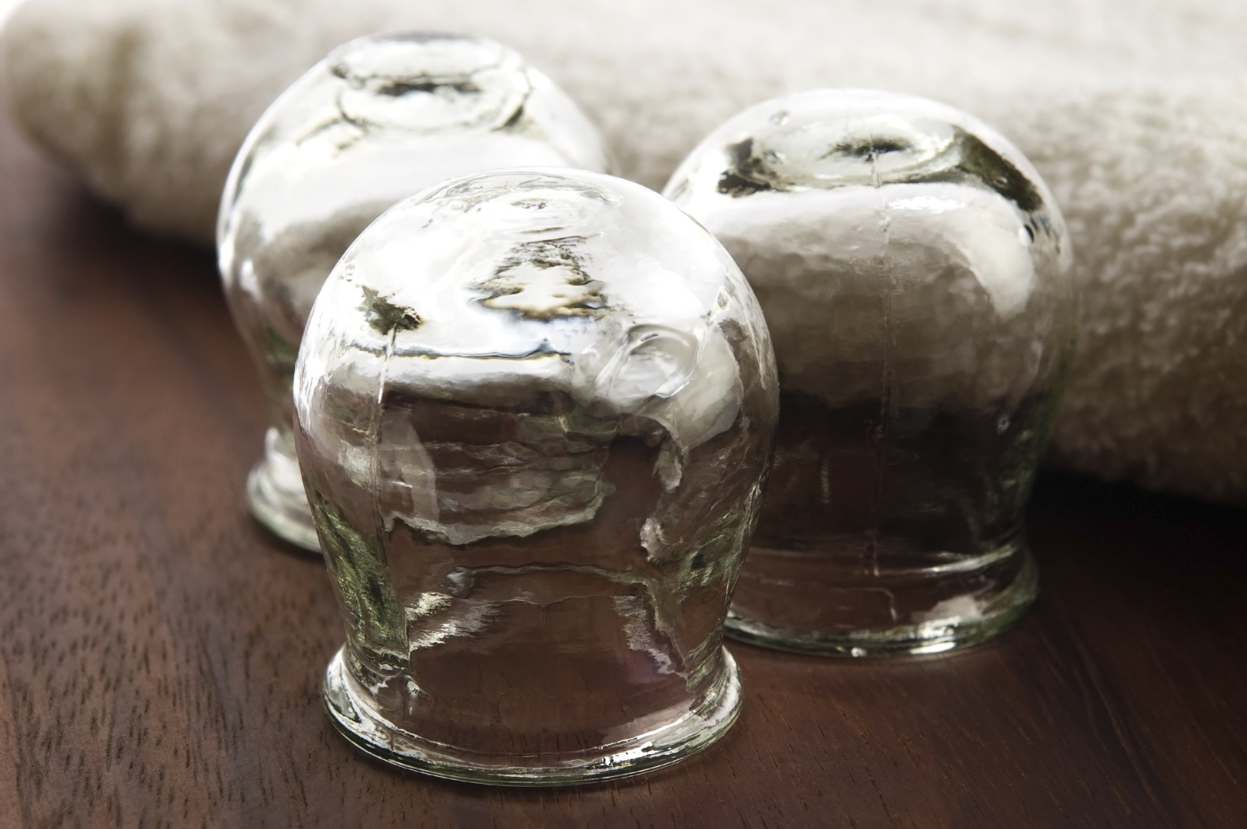 Nærbilde av glasskuler eller isskulpturer med reflekterende overflate, plassert på en trefarg.