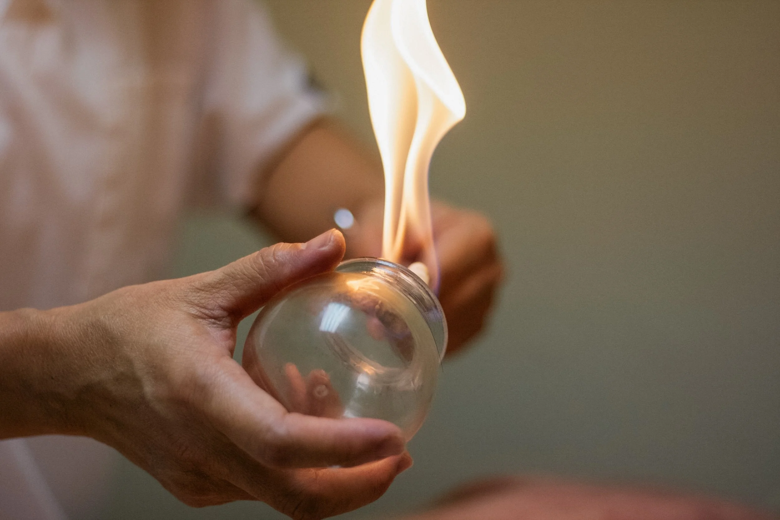 En person holder et transparent glass som er i ferd med å bli tent med en flamme.