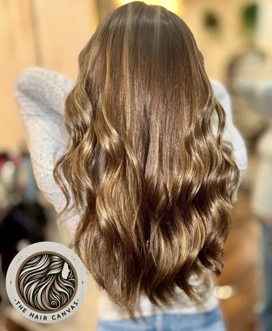 Warm glossy brunette hair color with long waves at The Hair Canvas in Ashland, KY.