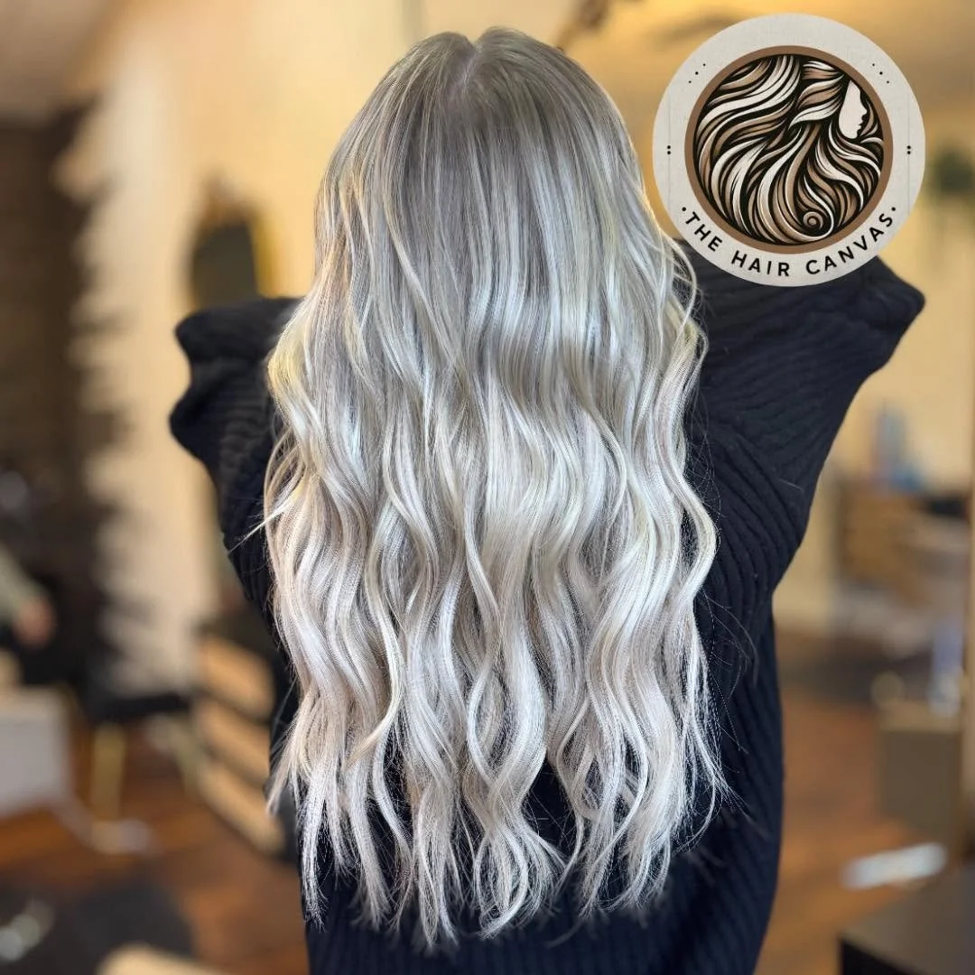 Long, wavy, blonde hair on a person with their back facing the camera in a salon setting.