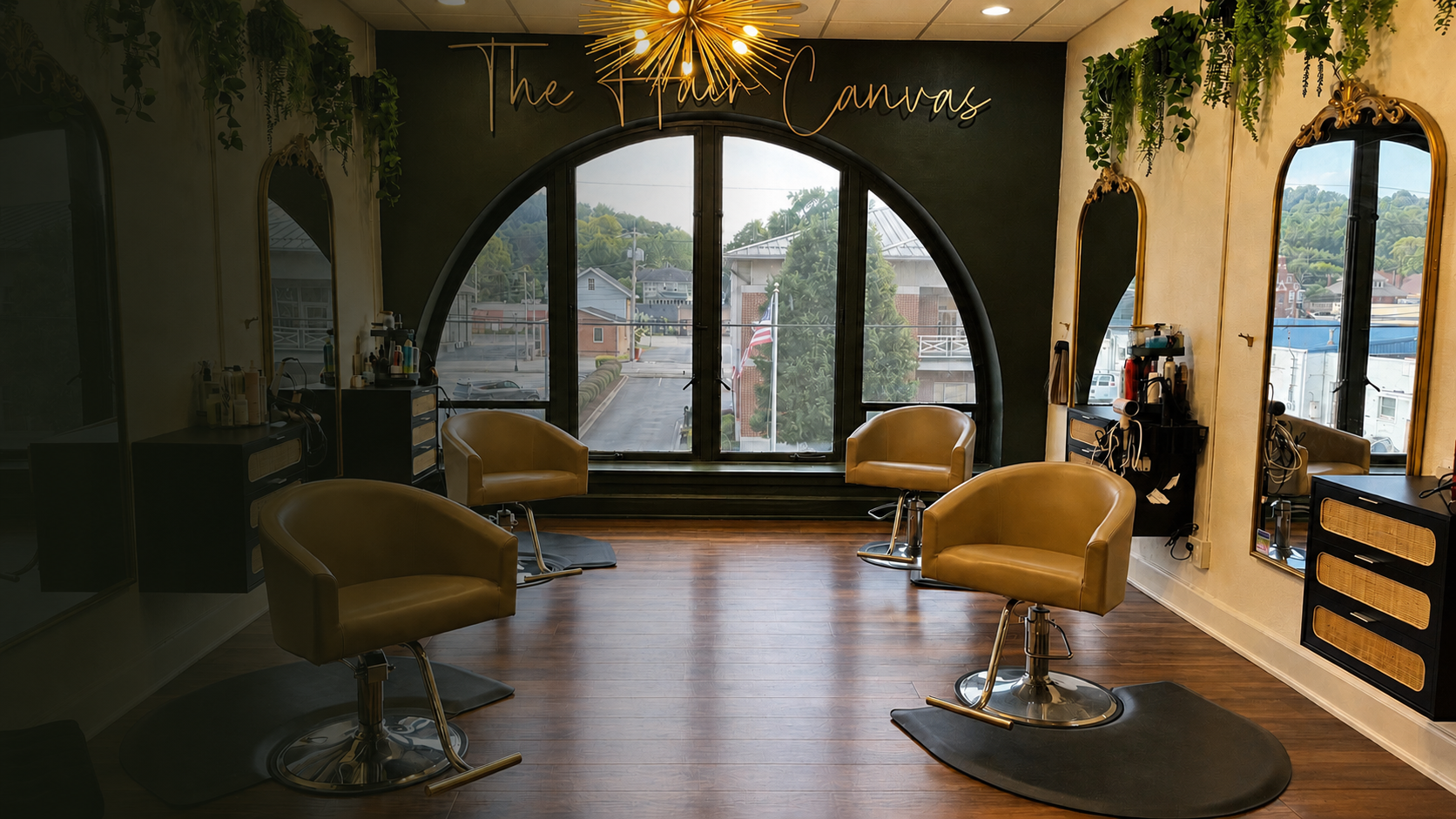 Interior of a hair salon with four yellow chairs, large windows, mirrors, and hair styling equipment, with greenery and a neon sign 'The Flawless Canvas' on the back wall.