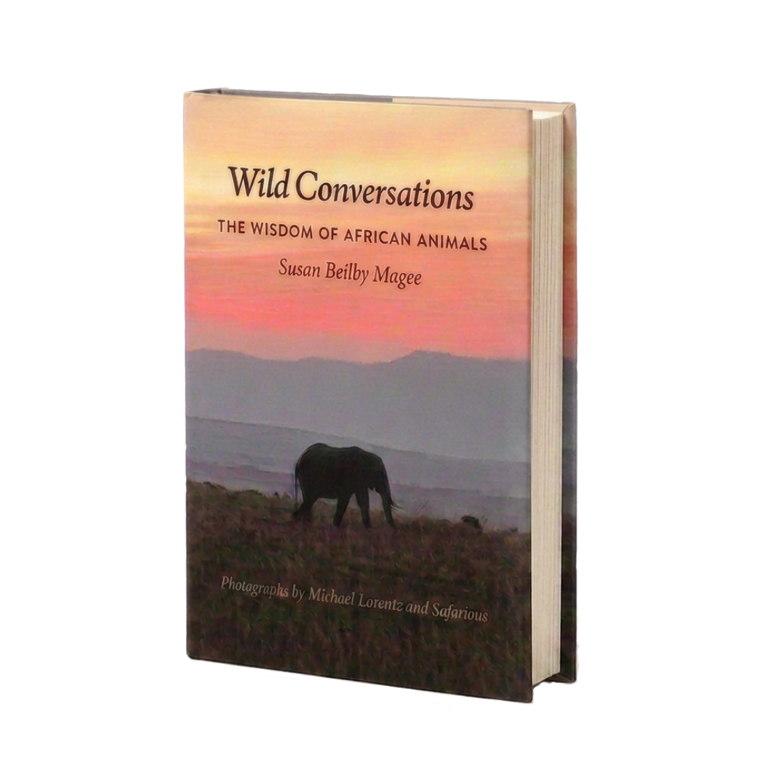 A hardcover book titled "Wild Conversations: The Wisdom of African Animals" by Susan Beilby Magee, featuring a silhouette of an elephant on a landscape with a sunset sky.
