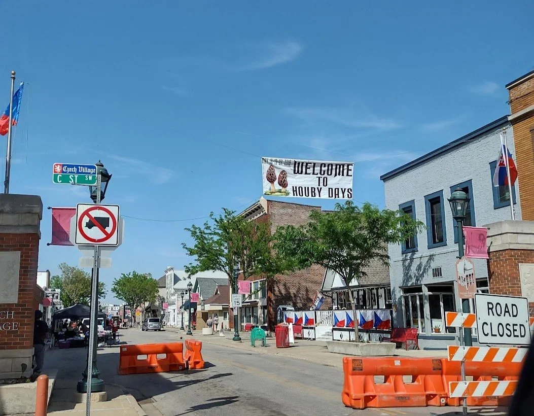 Downtown street scene with signs indicating road closure and no U-turn, decorated with pink banners. A 