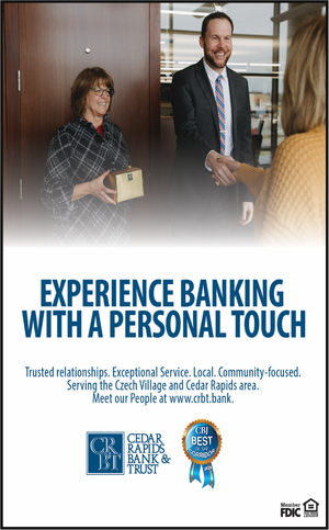 A bank teller in a checkered shirt hands a card to a smiling woman in a yellow sweater. The scene takes place in a bank lobby with a man in a suit observing and smiling.
