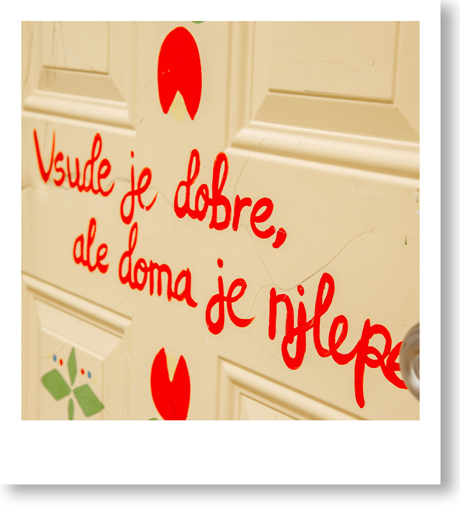Decorative door with a painted quote in red and colorful flower stickers.