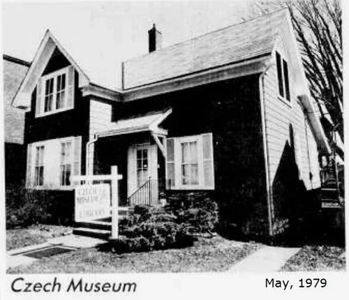 A black-and-white photo of a two-story house with a gabled roof, a small front porch, and a sign in the yard, dated May 1979, at the Czech Museum.