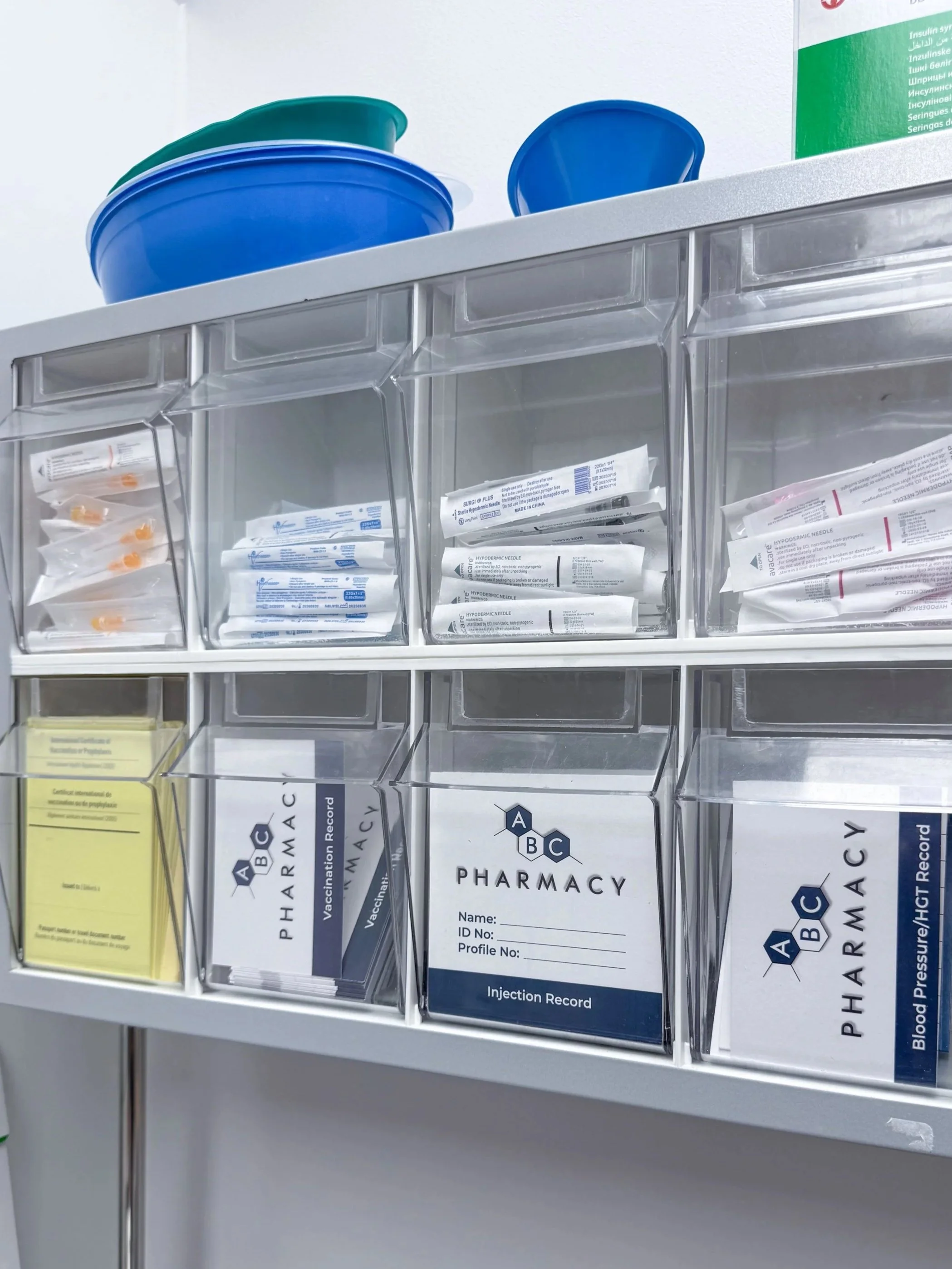 Clear plastic storage box with medical supplies including syringes and vaccination records, labeled ABC PHARMACY.