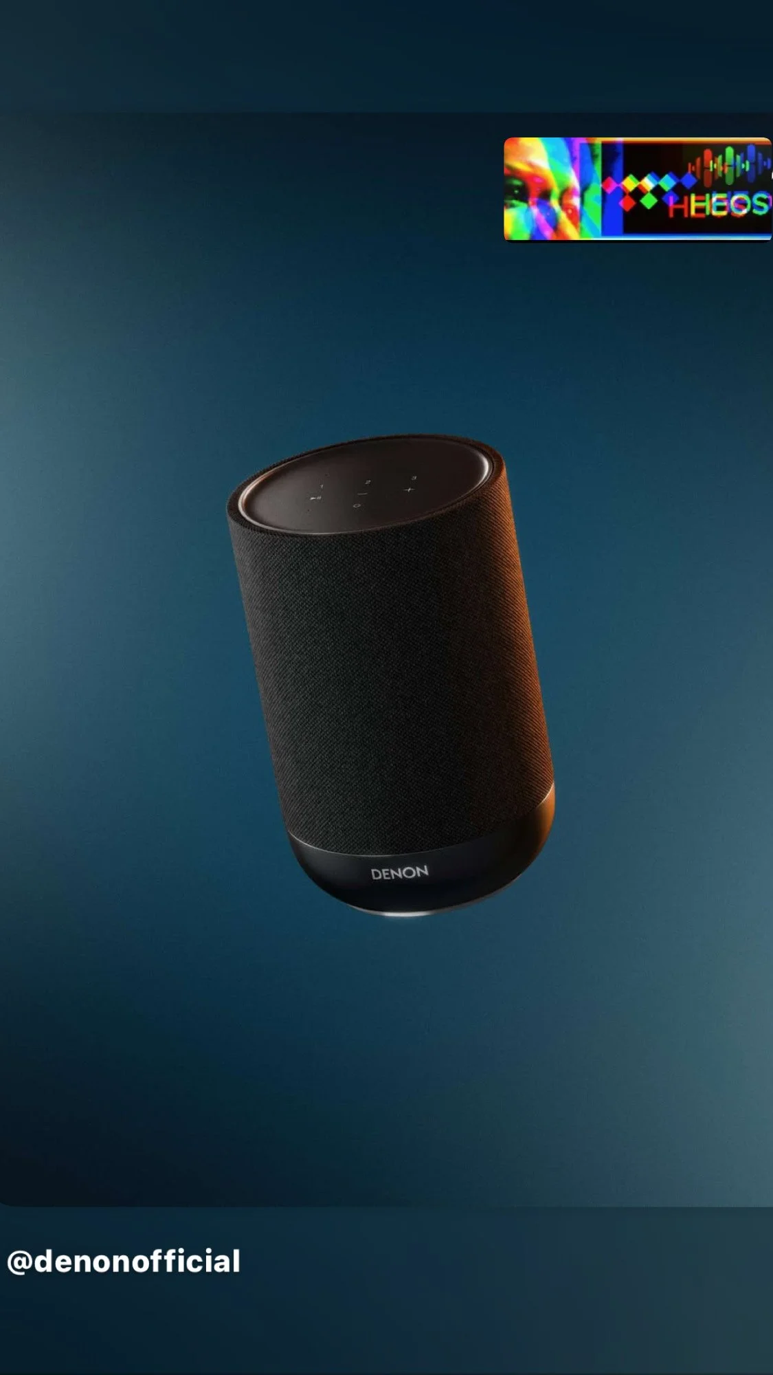 A black Denon portable speaker with a fabric exterior on a dark blue background, with the top control panel visible. The image includes a colorful, psychedelic profile of a person's face with the text '@denonofficial' at the bottom left corner.