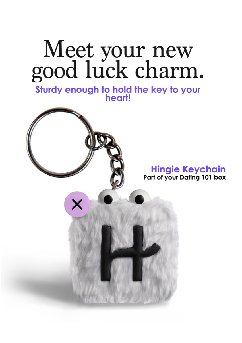 Close-up of a keychain with Hingie, the Hinge app mascot, who has a fuzzy square body, two googly eyes and a black letter H. Hingie is hanging from a silver keyring and chain, on a plain white background.