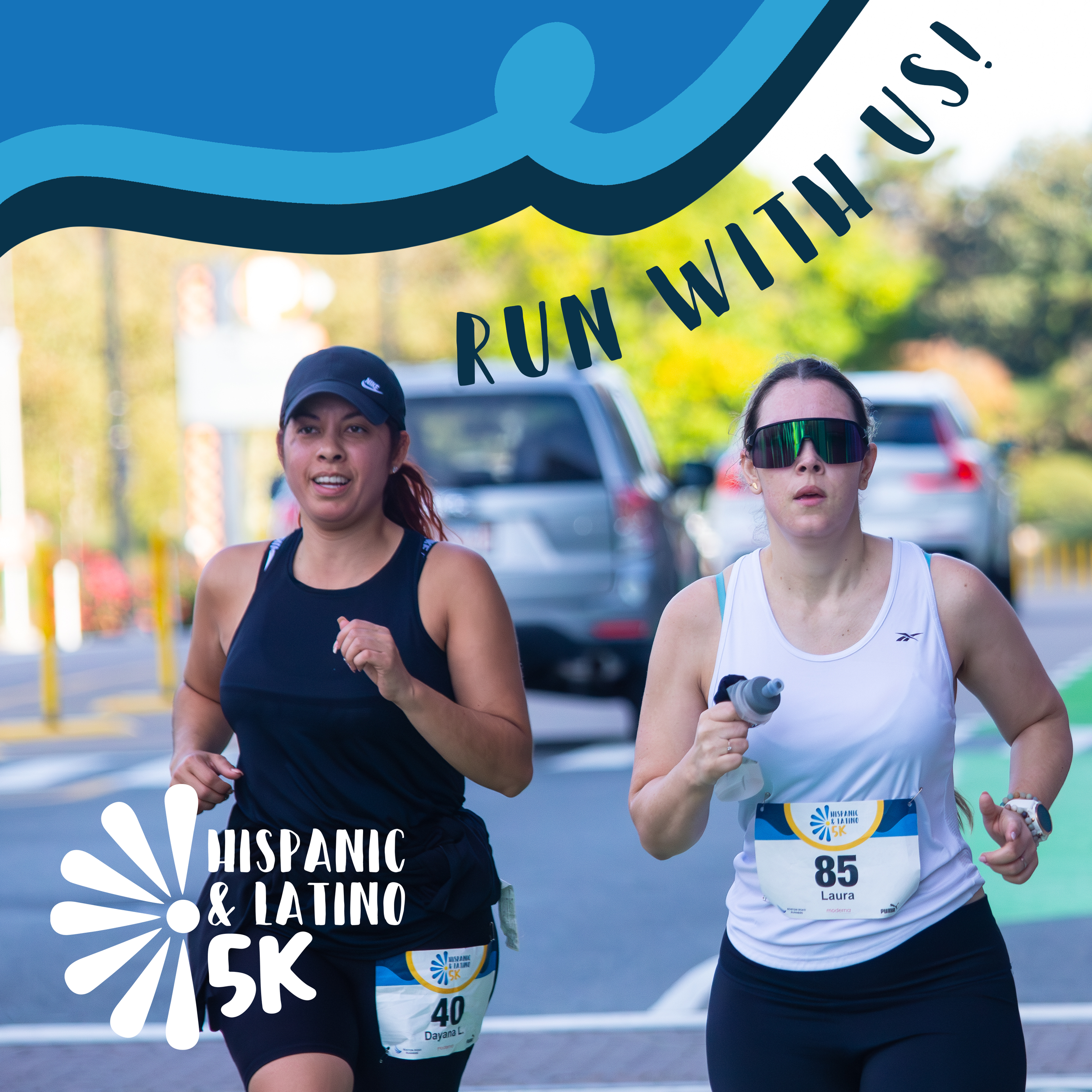 Two women running in a race outdoors, wearing sports attire and race bibs, with trees and parked cars visible in the background.
