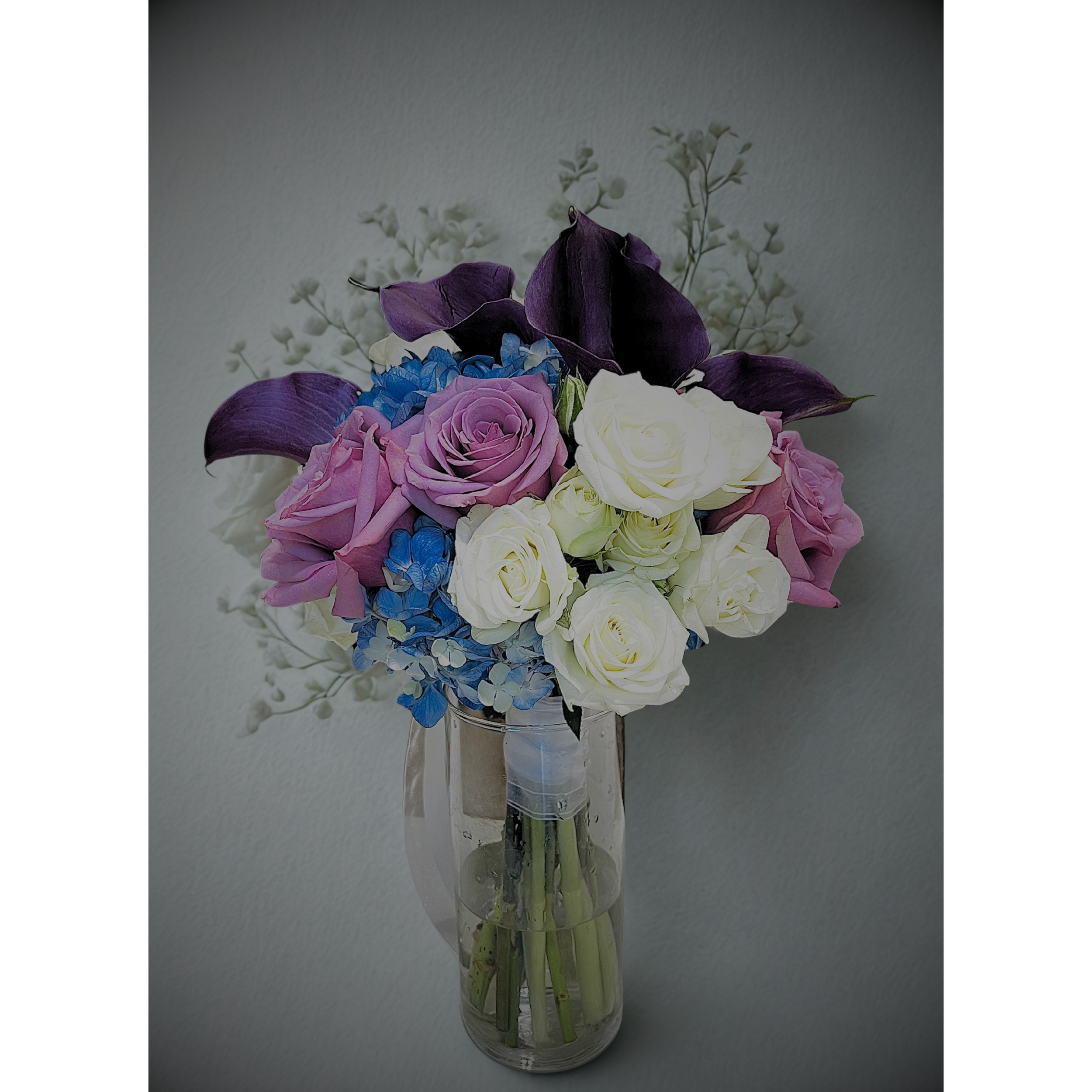 A bouquet of purple, pink, white, and blue flowers in a clear glass vase.