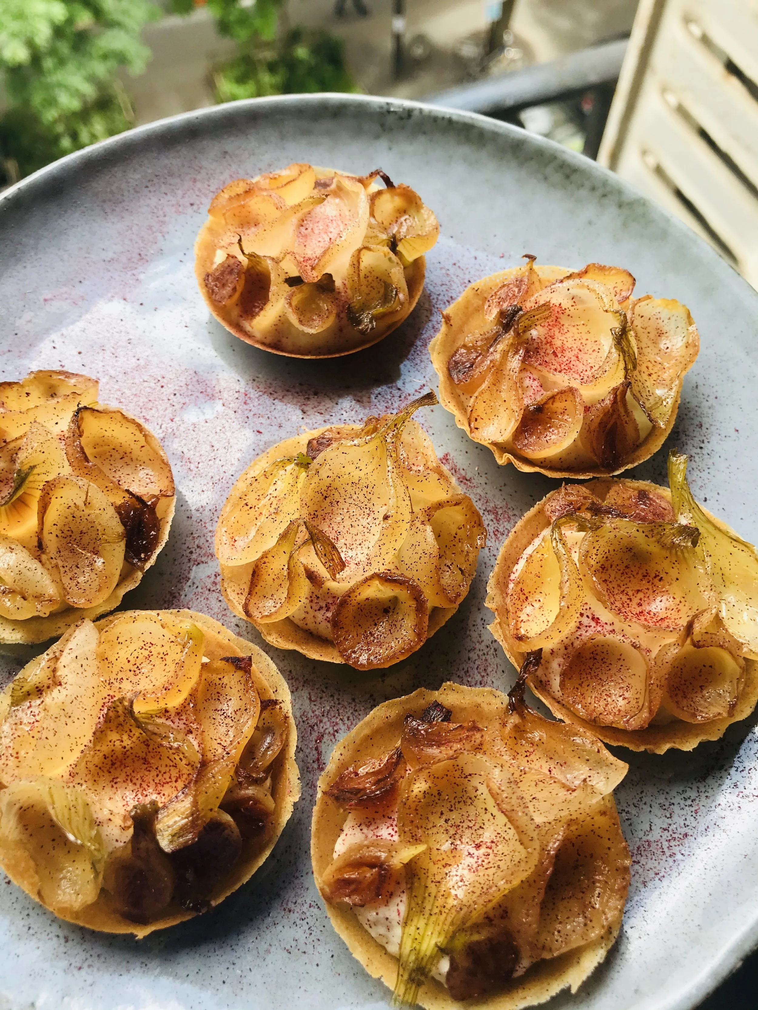 Mini tartes salées garnies de pommes de terre, fromage, champignons, et herbes, servies sur une assiette