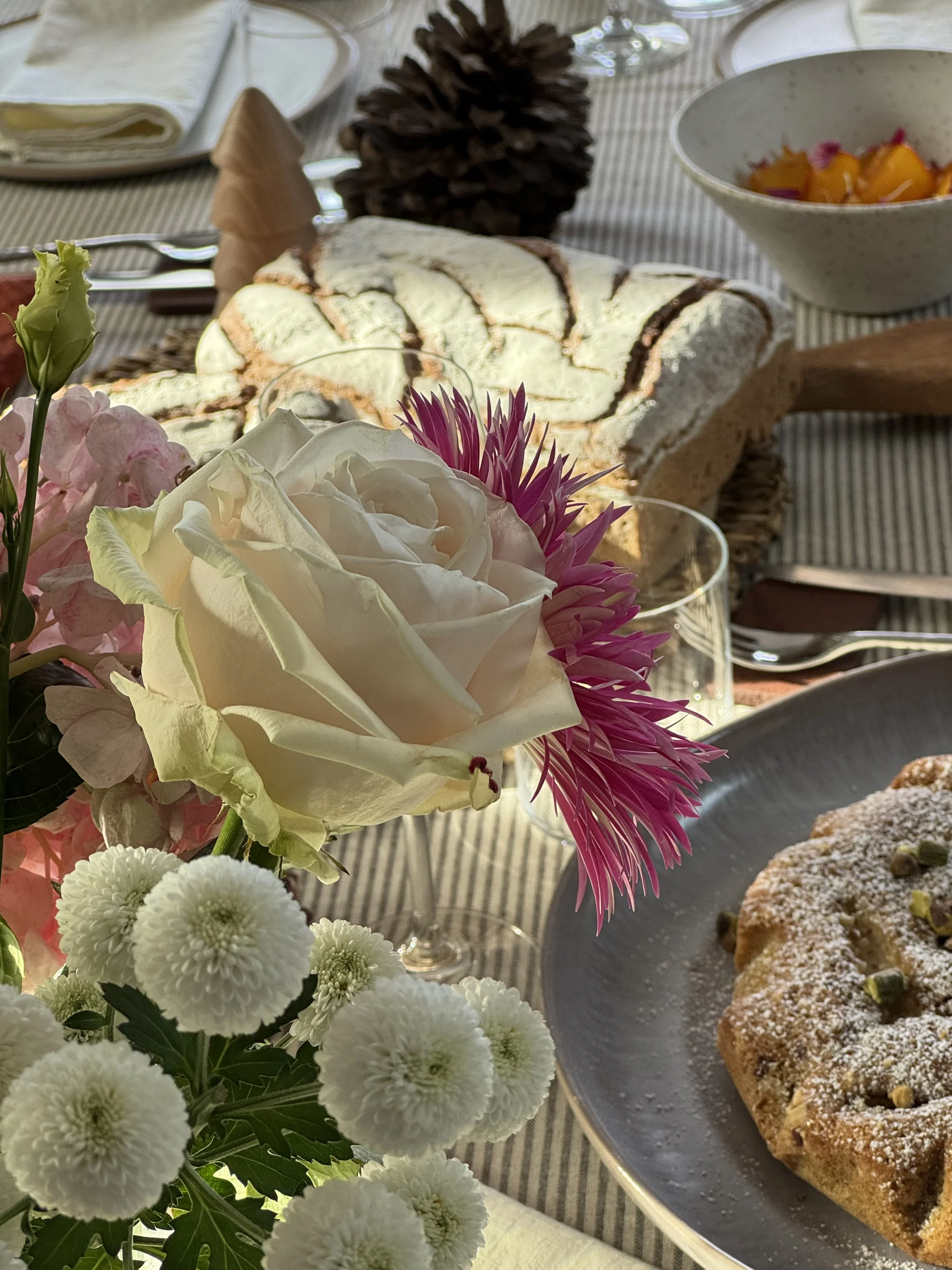 Bouquet de fleurs avec roses blanc et autres fleurs colorées sur une table, à côté d’un plateau avec un gâteau aux fruits