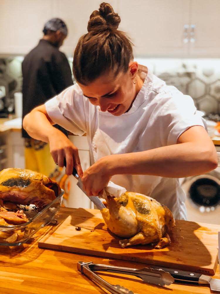 Une femme en chef prépare un plat de viande dans une cuisine.