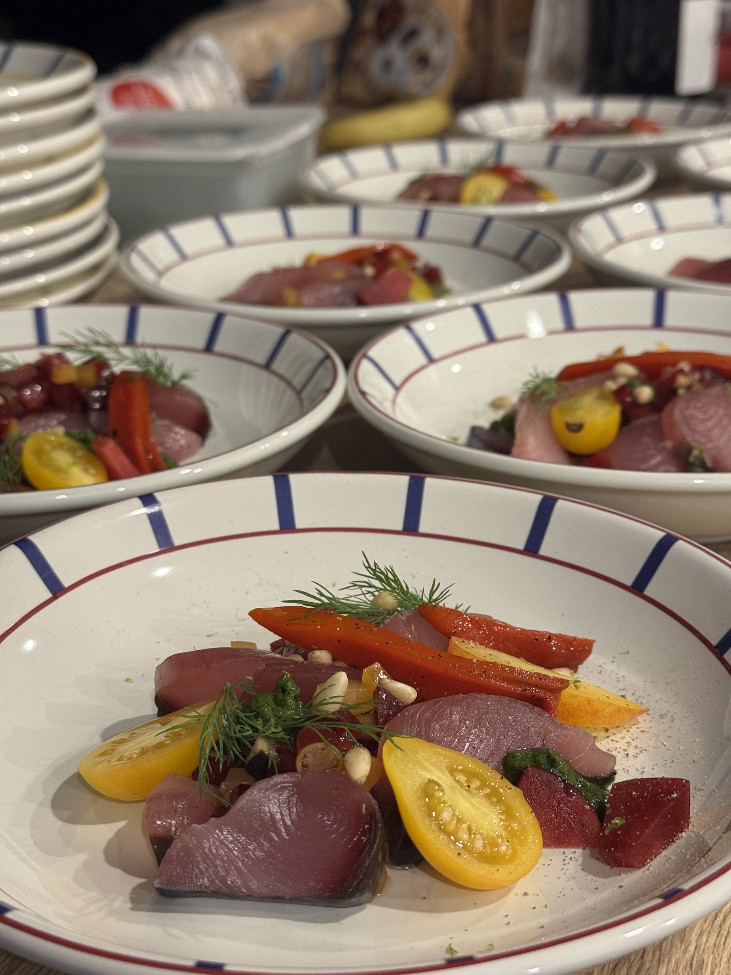 Assiette de carpaccio de poisson avec des tomates jaunes et rouges, des herbes et des olives.
