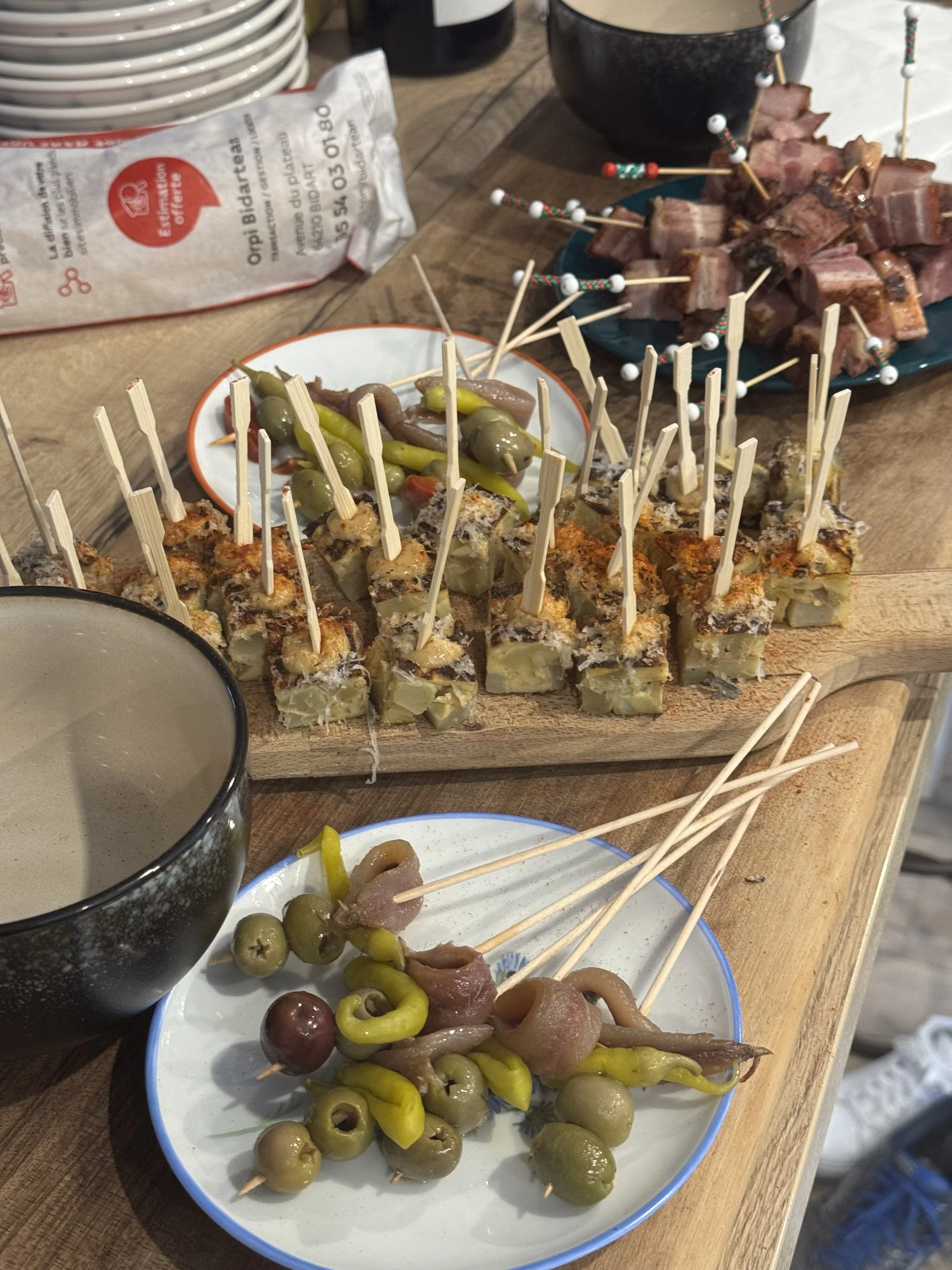 Plateau avec des brochettes de viande, olives, poivrons, et autres légumes, avec un bol de sauce ou dip.
