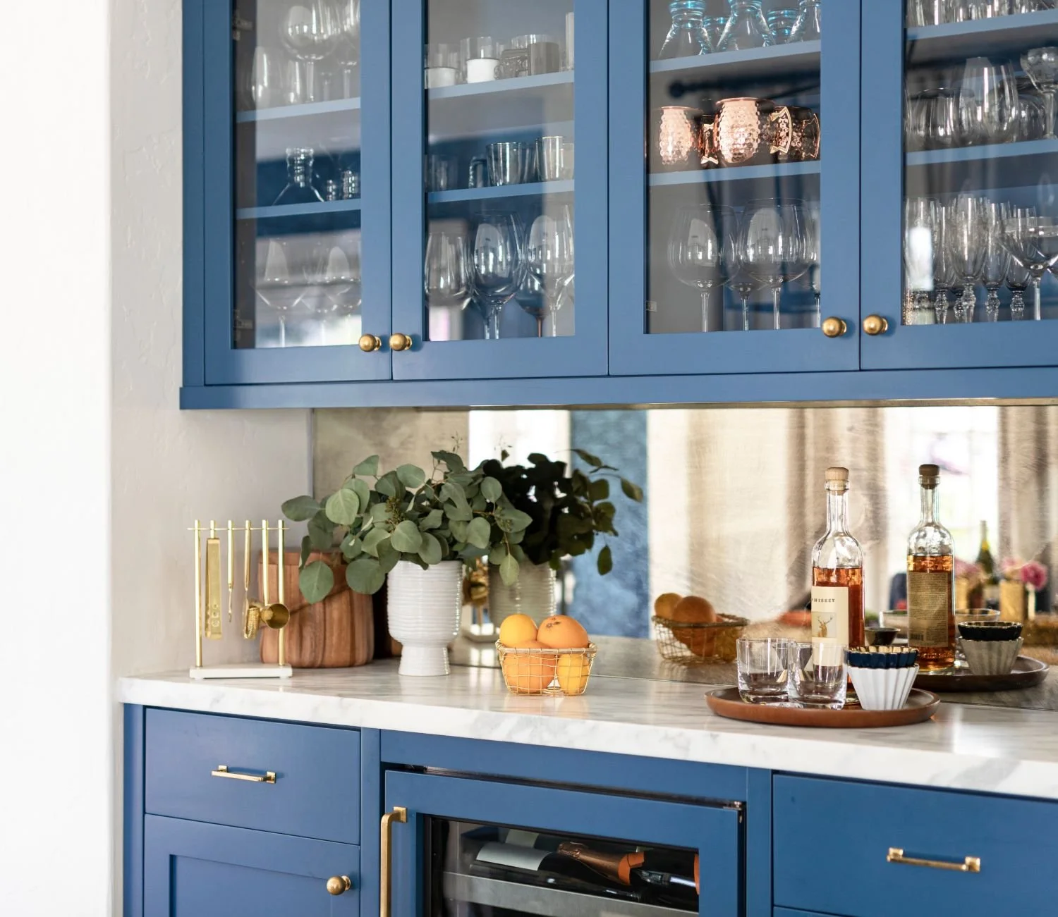 Built-in blue cabinetry with organized glassware, bar accessories, and serving essentials.
