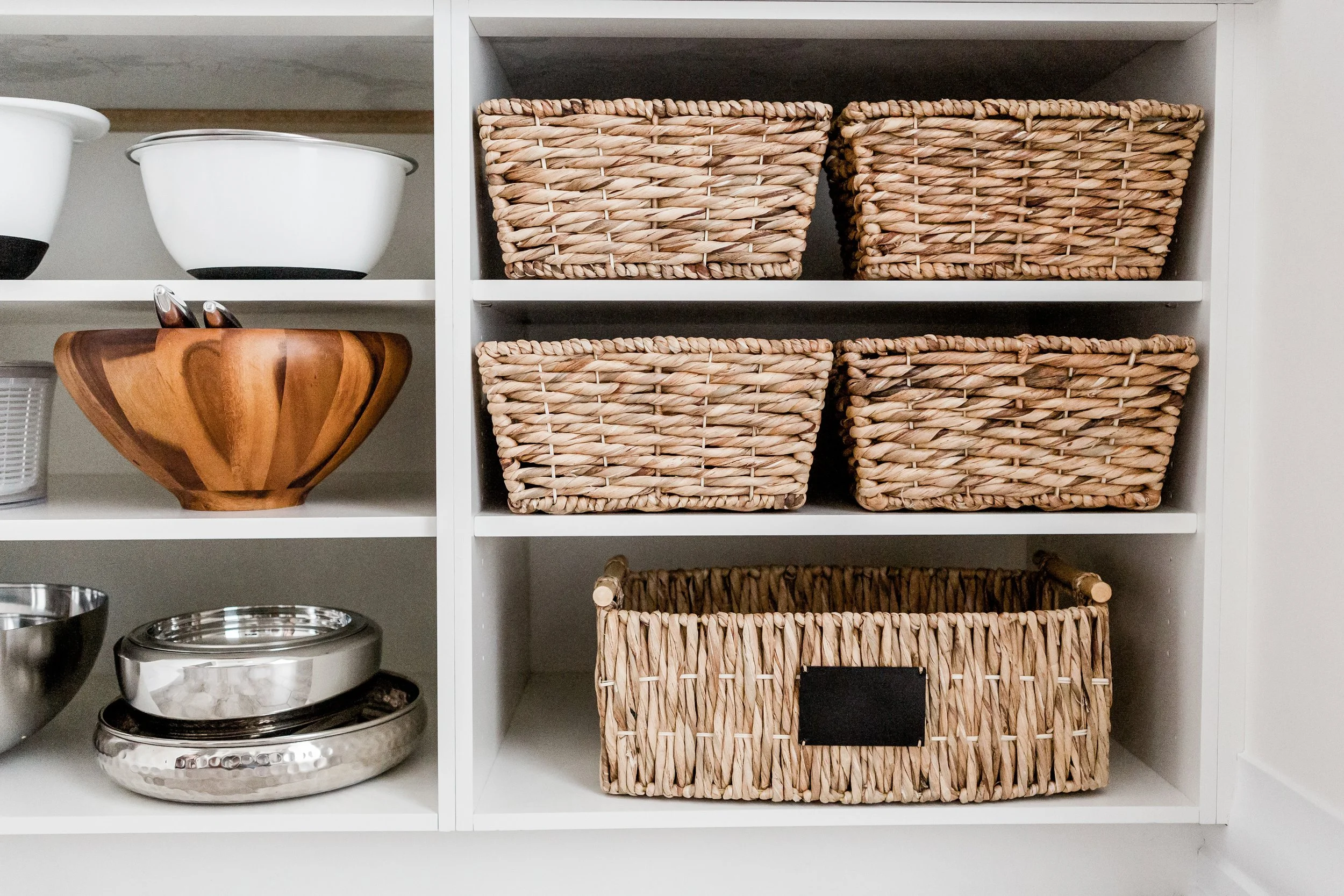 Built-in pantry shelves with decorative woven baskets for organized kitchen storage.