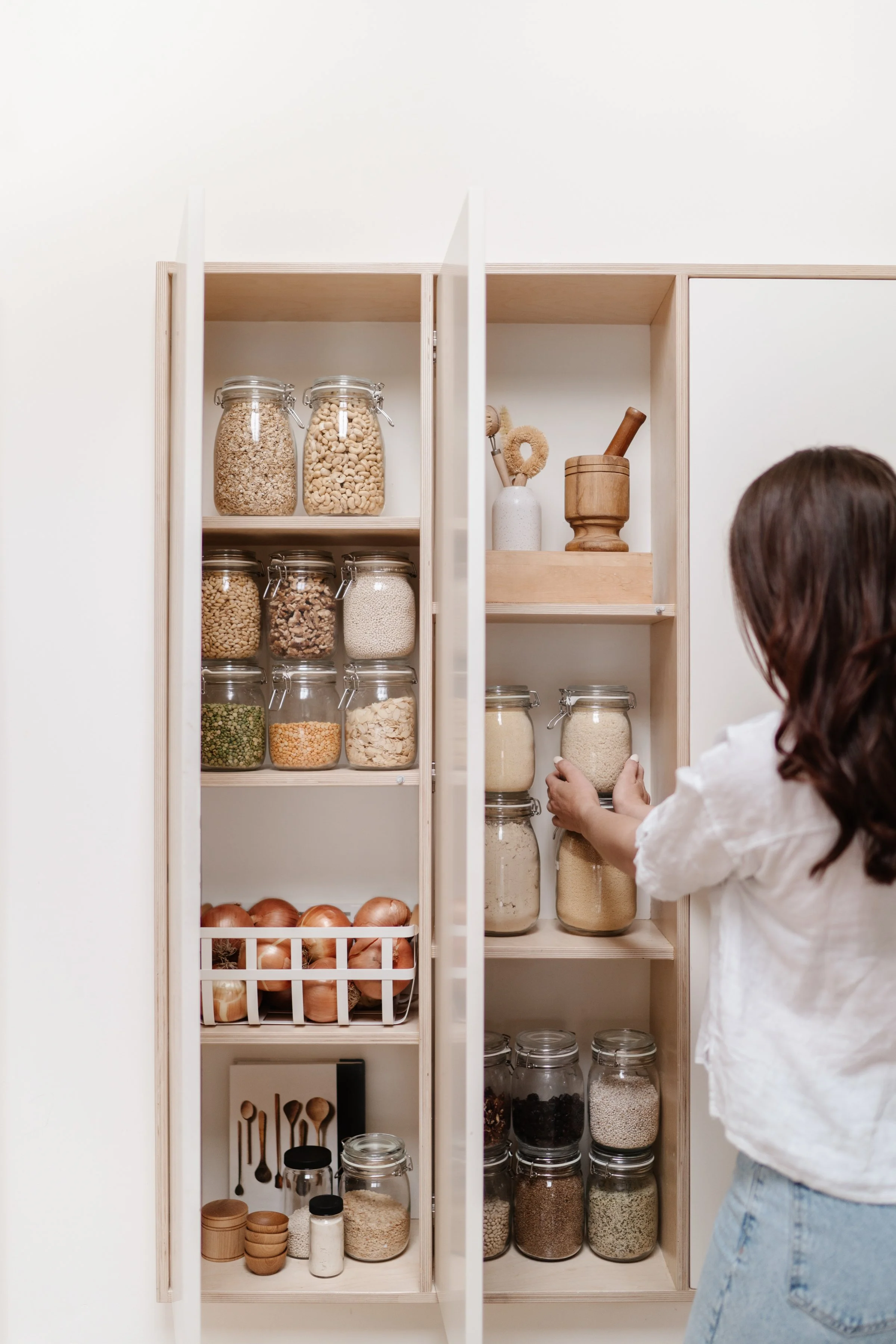 Pantry organization with labeled glass jars, grains, spices, and kitchen essentials.
