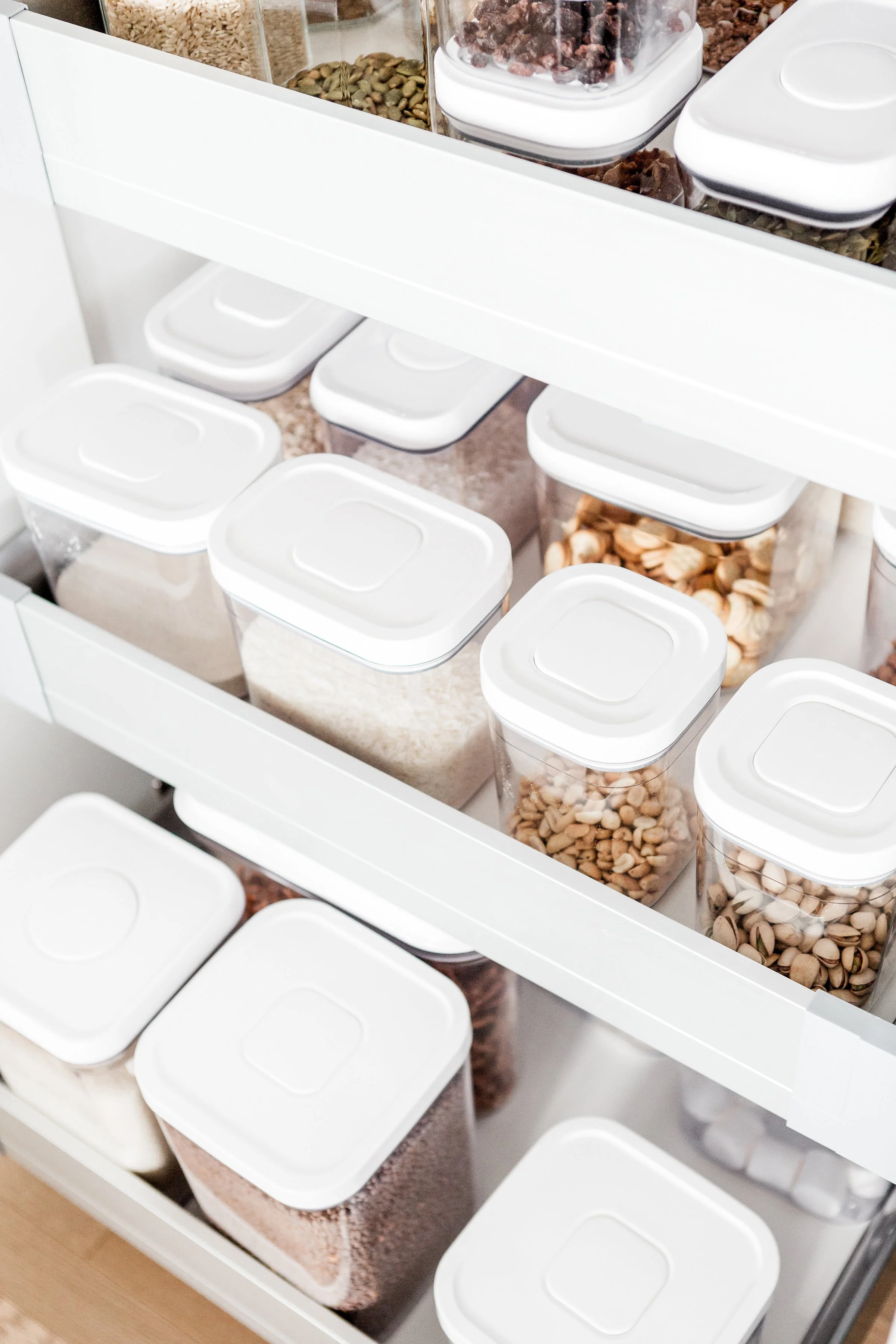Clear pantry storage containers neatly organized in a pull-out kitchen drawer.