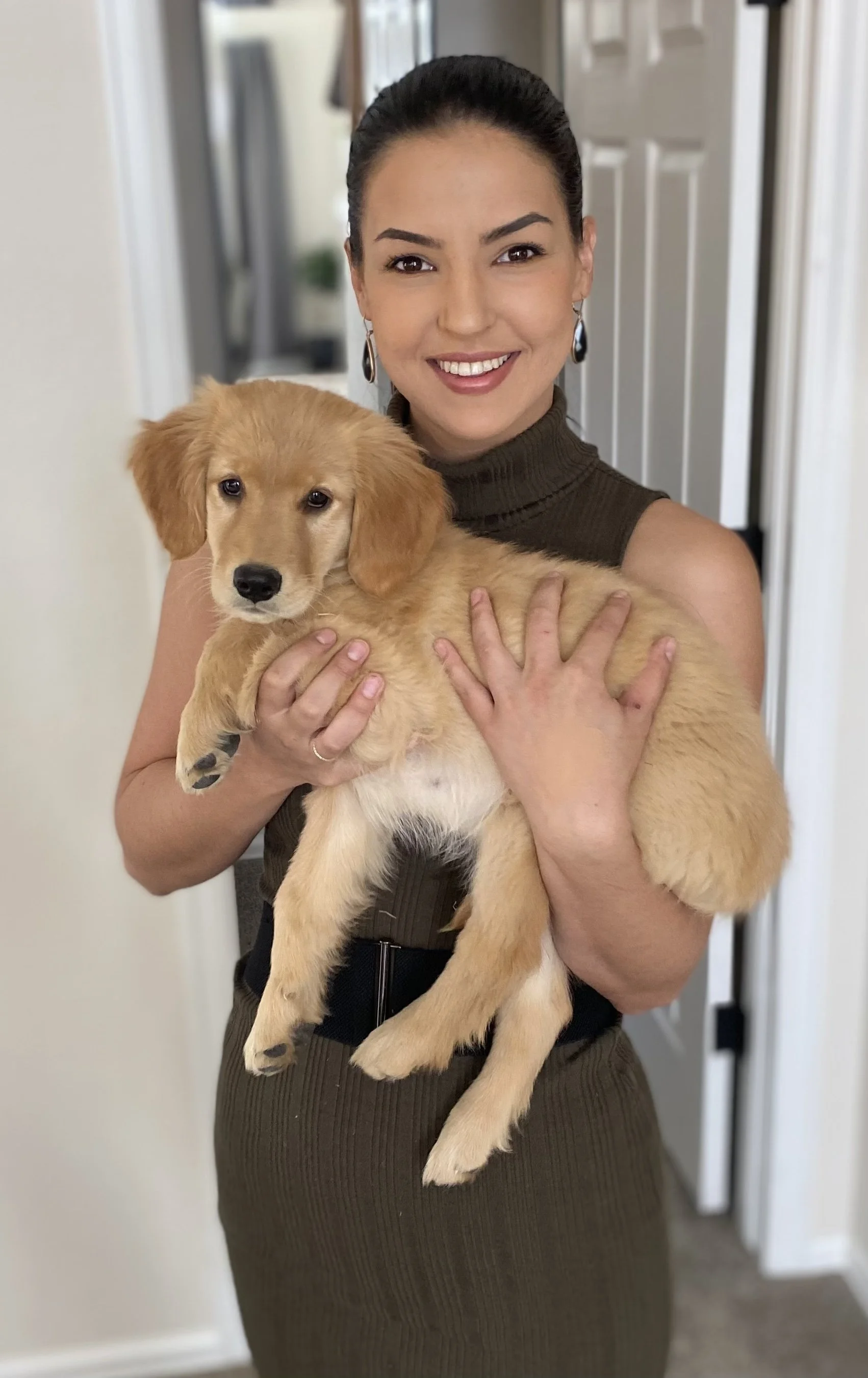Portrait of a professional organizer holding a golden retriever puppy indoors.