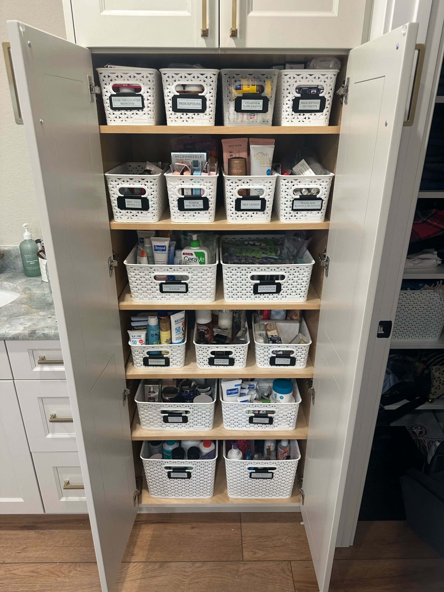 Linen closet organized with labeled bins for cleaning supplies, toiletries, and household essentials. 