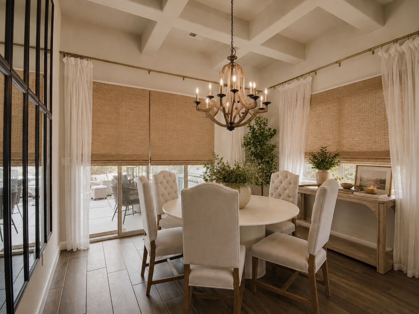 Woven shades, airy linen drapery, a softly weathered wood console, and a wall of mirrors that amplifies light and depth - all bring warmth and intimacy to this light-filled dining space.