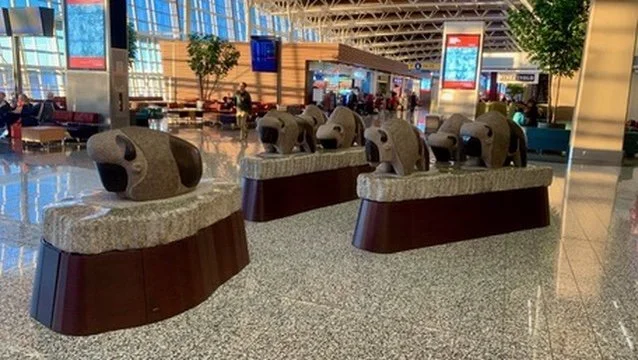 Seating area at an airport with stone elephant-shaped sculptures on top of benches.