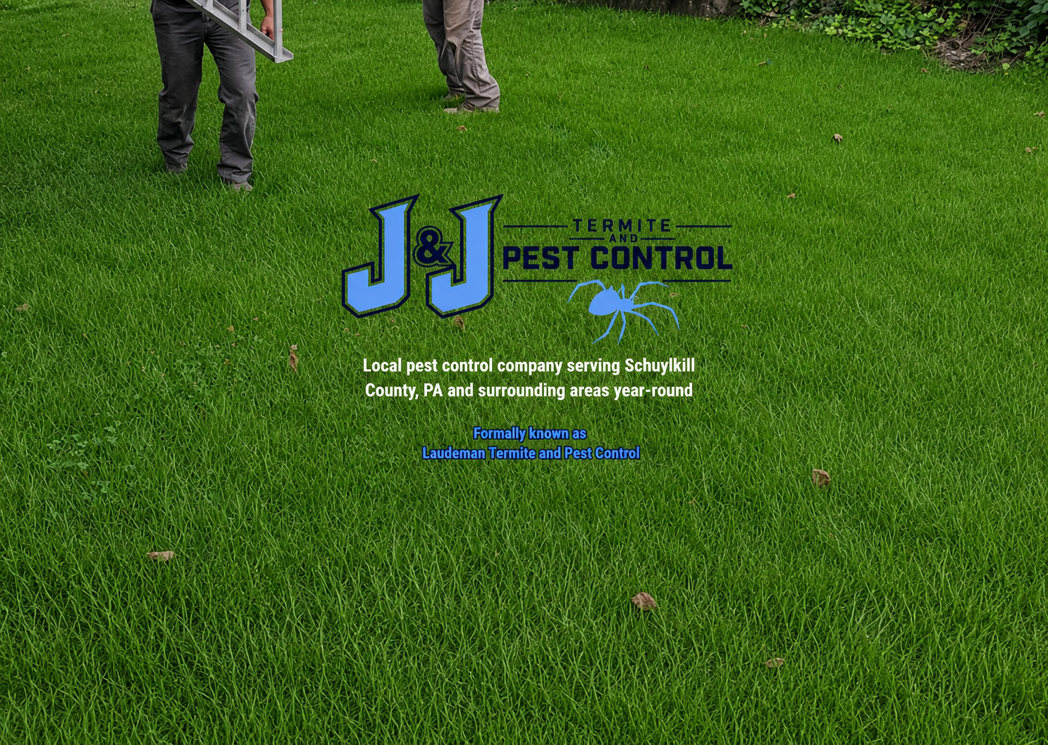 A lawn with a logo for J&J Termite and Pest Control, featuring large blue letters 'J&J' and a blue termite graphic. Two men are partially visible in the background, handling equipment on the grass.