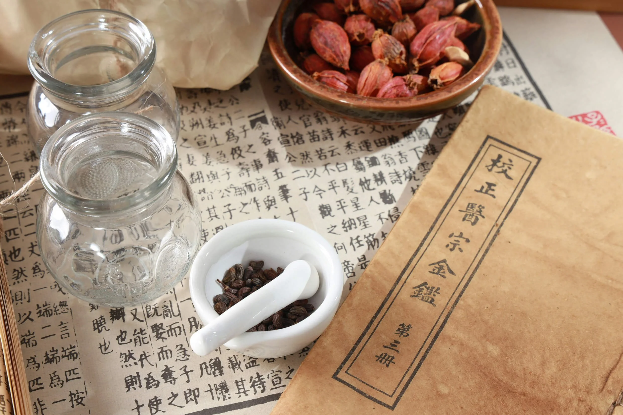 A tabletop with a small white dish with herbs and a paper with Chinese writing at New Heights Acupuncture and Chinese Medicine during TCM assessment.