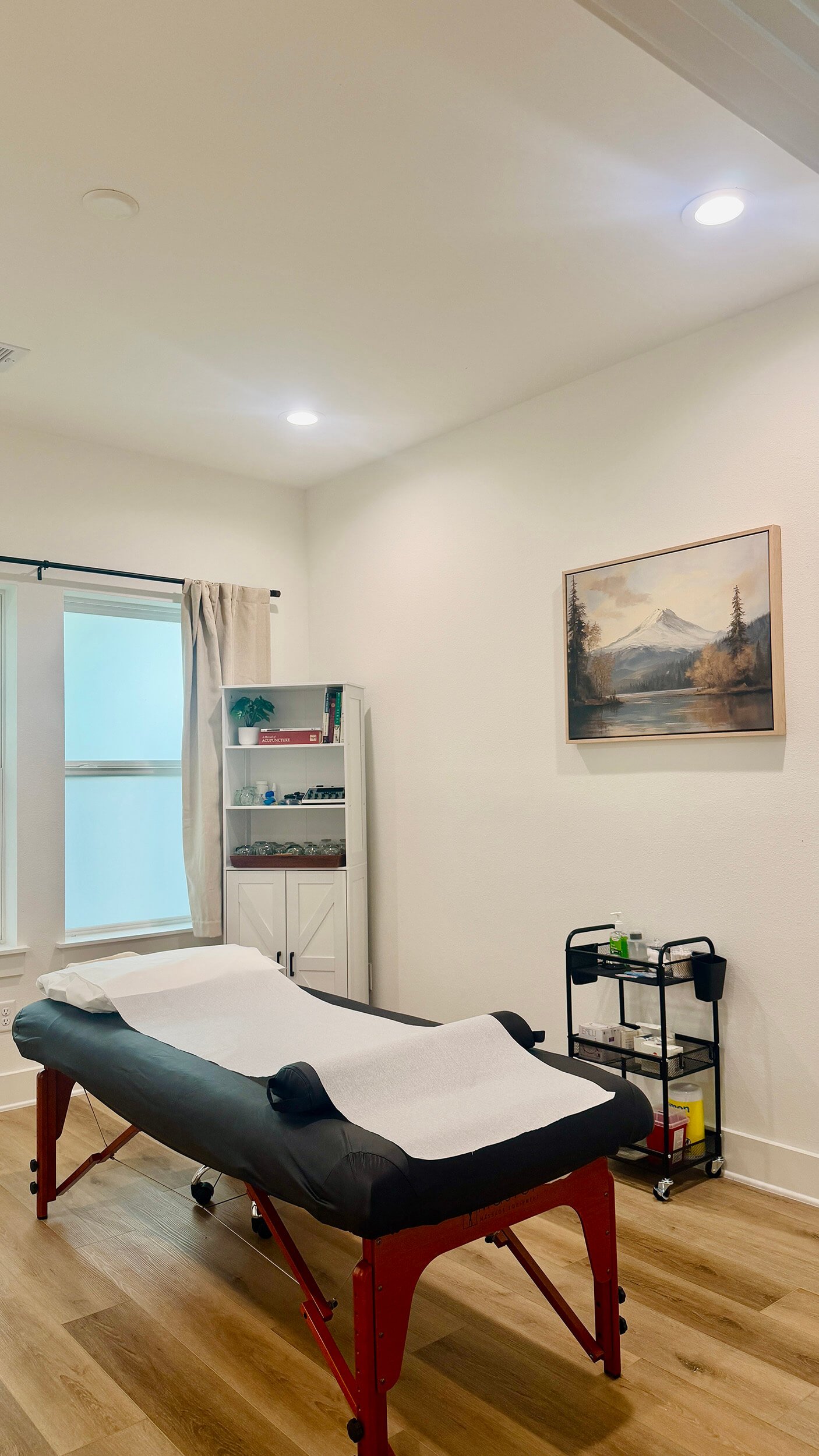 A massage table with a cushion and rolled towels in a well-lit room at New Heights Acupuncture and Chinese Medicine in Houston, Texas.