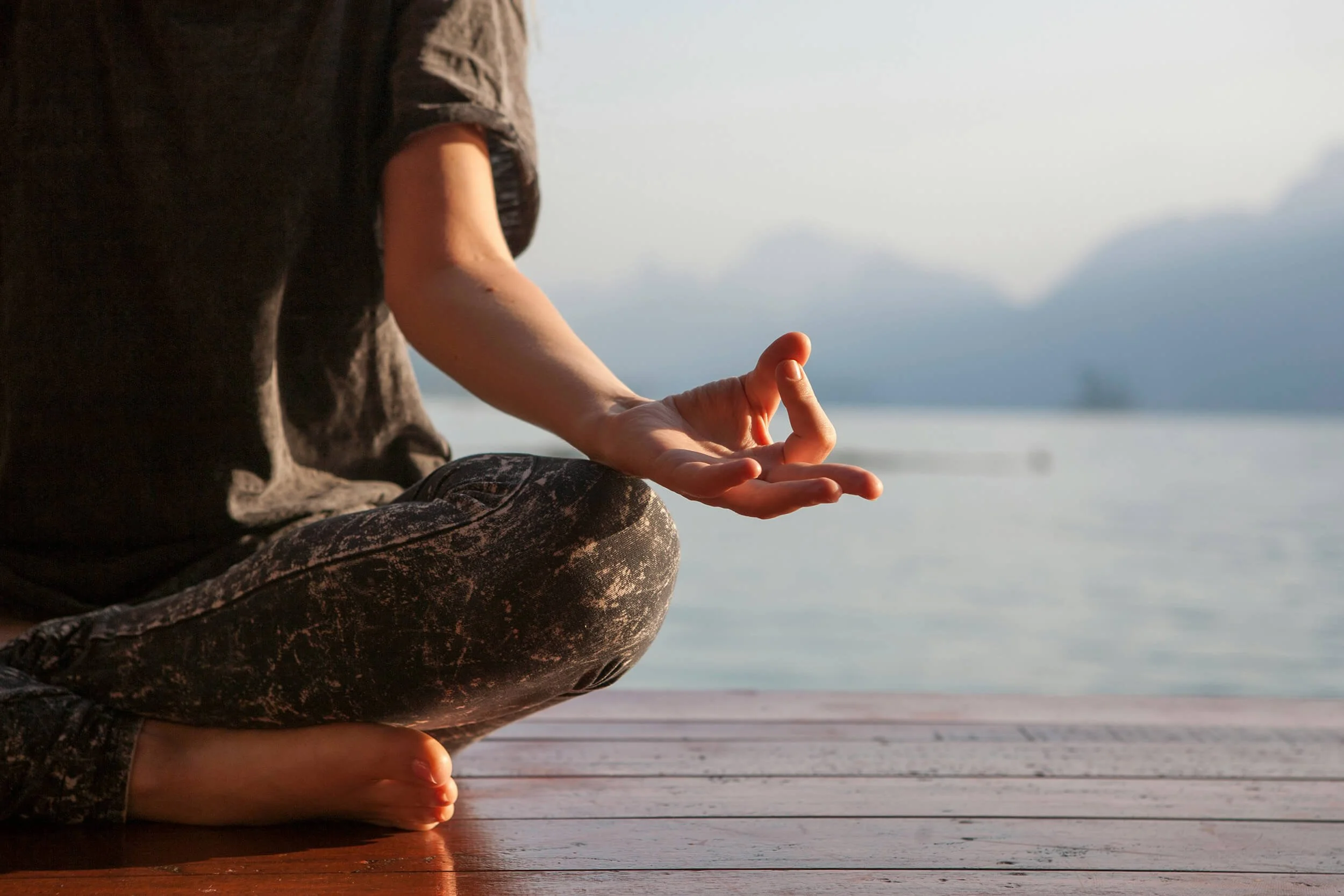 Person practicing meditation outdoors near a body of water after acupuncture for women's health and fertility at New Heights Acupuncture and Chinese Medicine in Houston, Texas.