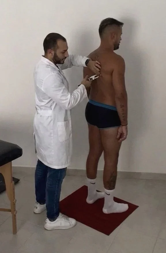 Un uomo riceve una vaccinazione o una presso in schiena da un medico in un'ambiente clinico, mentre si trova su una pedana rossa.