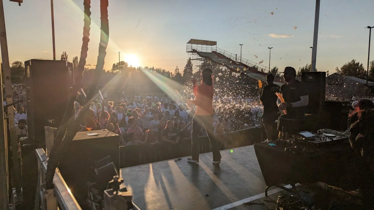View from the stage as a DJ entertains a large crowd at sunset at the Puyallup fairgrounds.