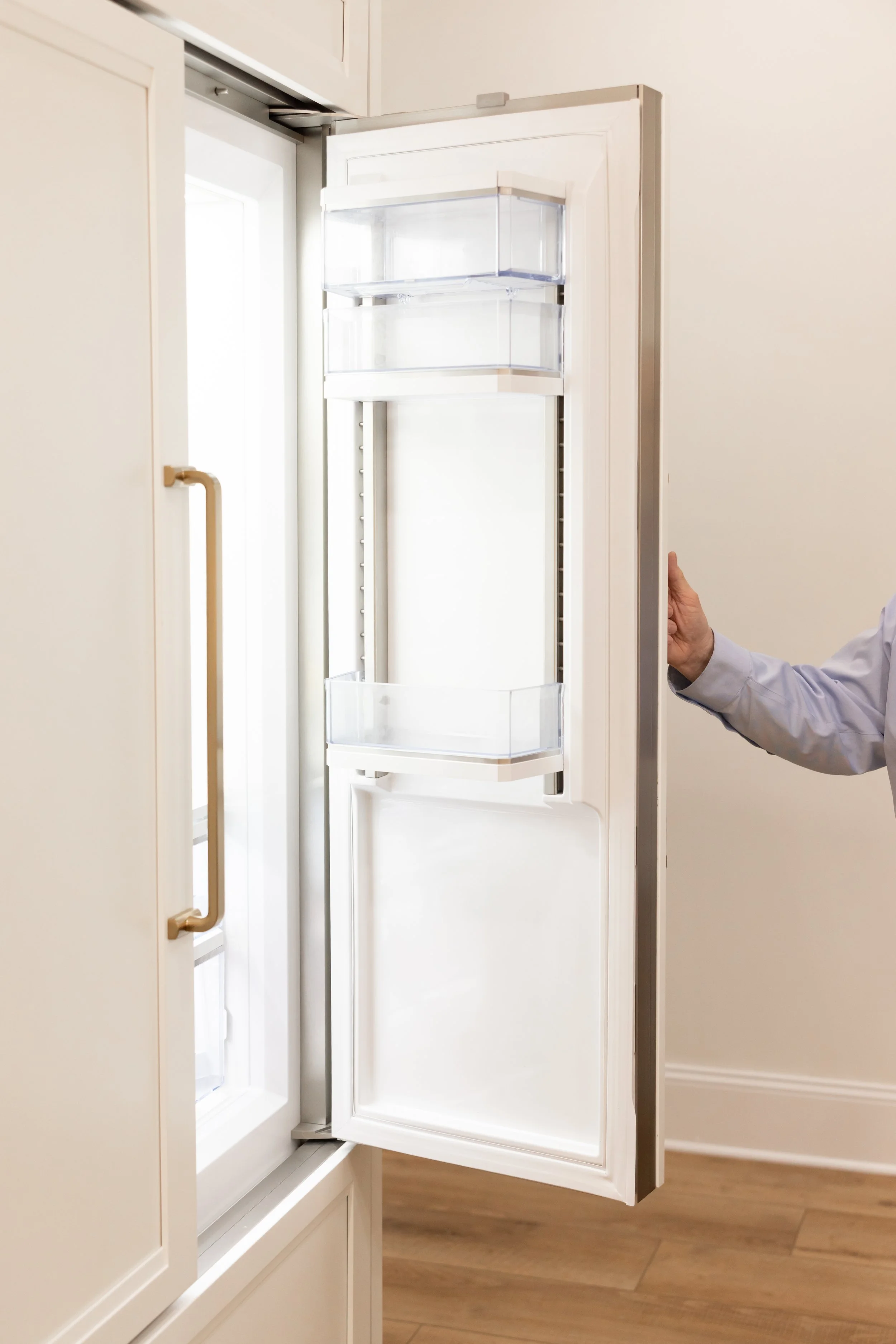 Empty white refrigerator door opened, revealing empty shelves and compartments.