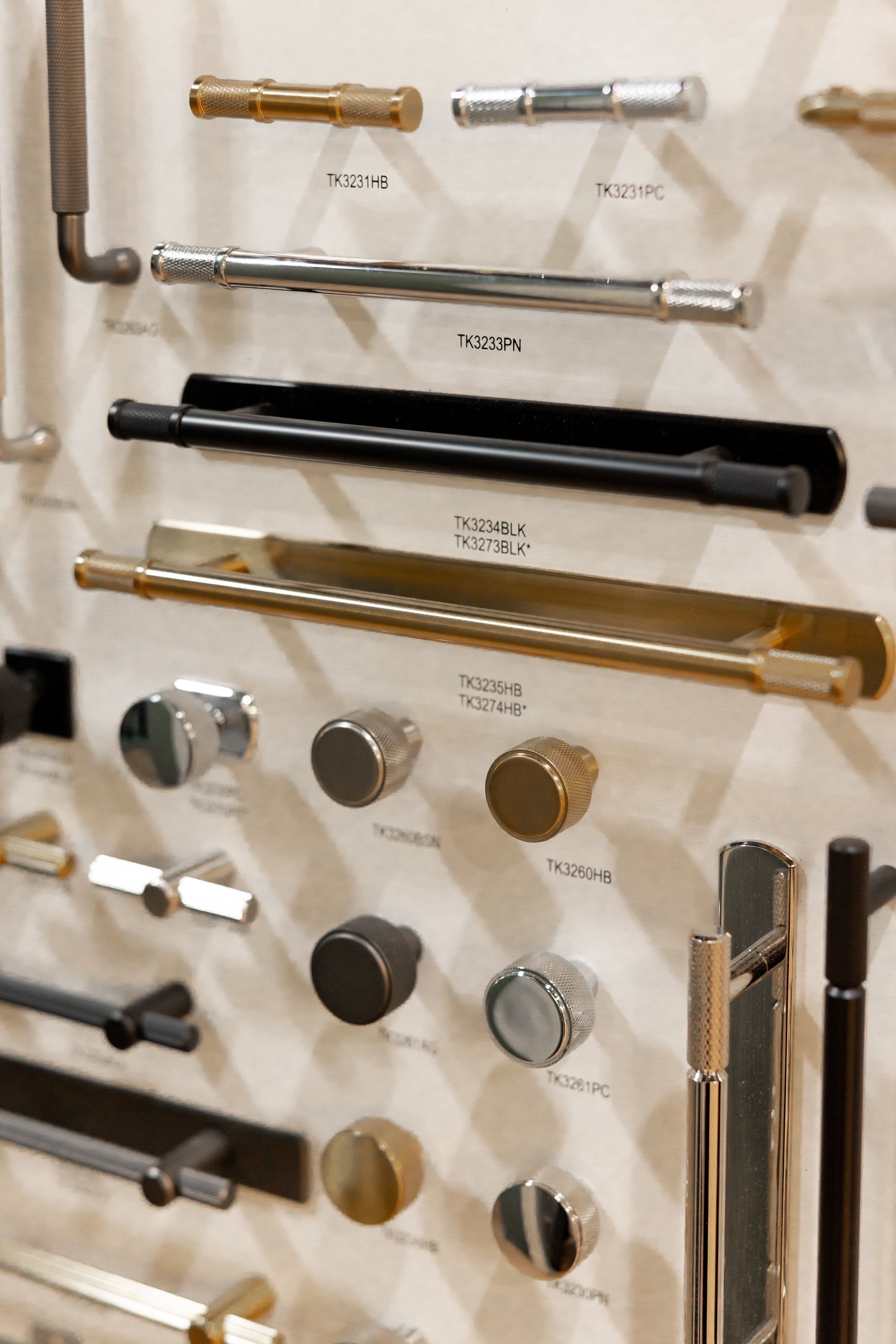 Display of various metal hardware pieces, including rods, knobs, and adapters, attached to a beige background with labels.