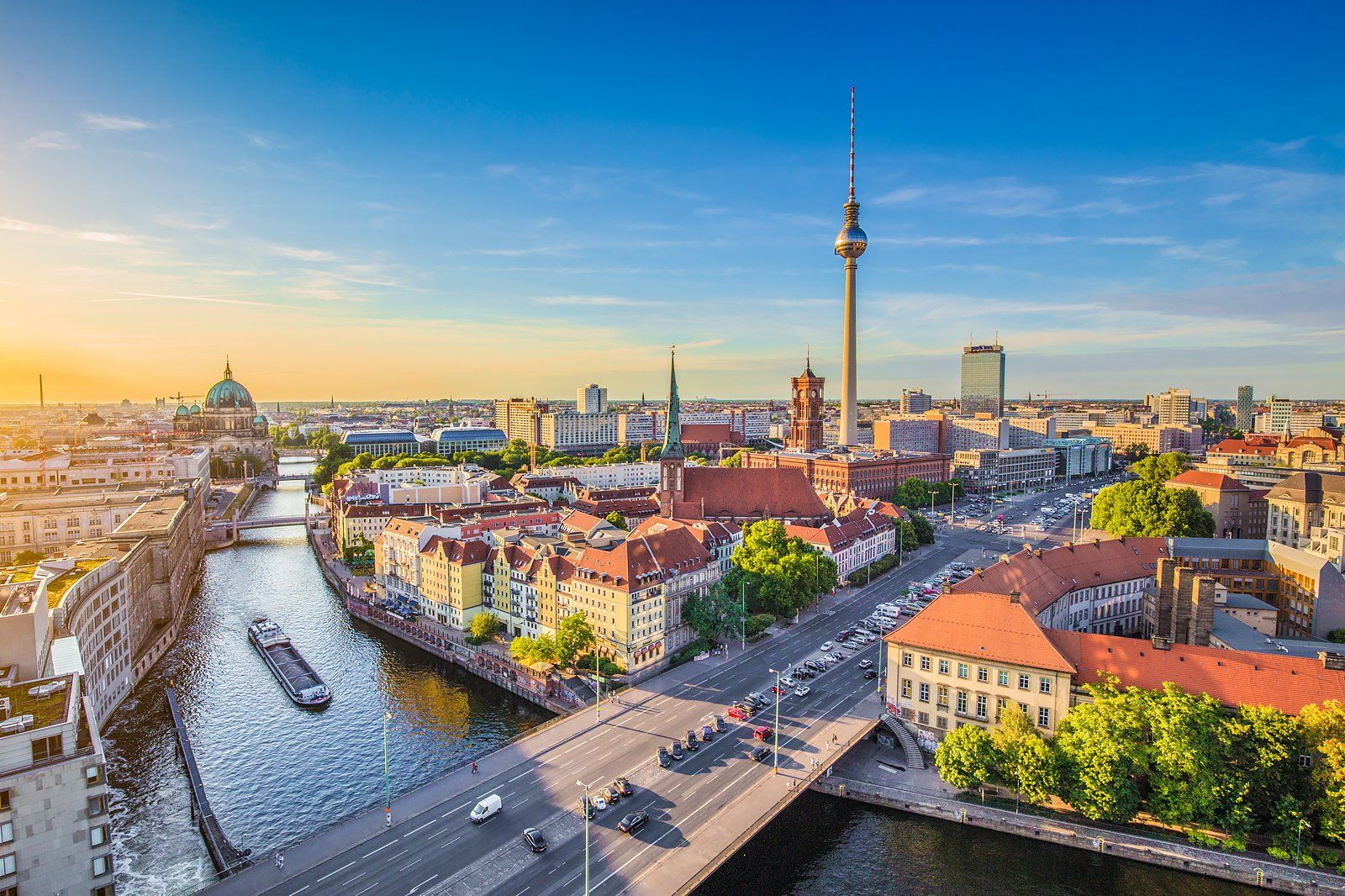 Vue aérienne de Berlin au coucher du soleil, incluant la tour de la télévision, la cathédrale et des bâtiments sous un ciel bleu.