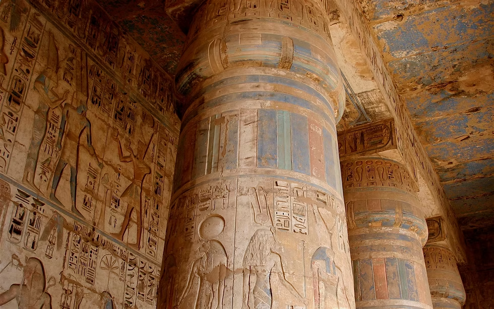 Intérieur d'une ancienne tombe égyptienne ornée de hiéroglyphes et de peintures murales sur des colonnes.