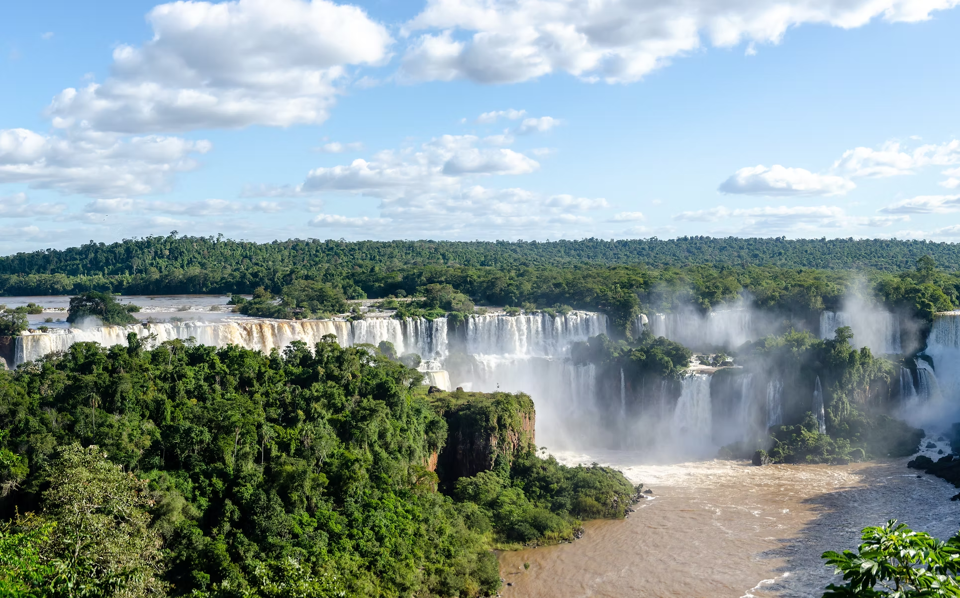 Chutes d'eau au milieu d'une forêt dense sous un ciel en partie nuageux.