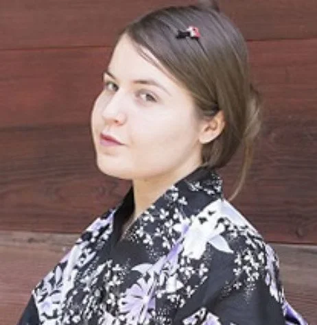 Jeune femme portant un kimono floral avec un fond en bois, cheveux bruns attachés avec une pince.
