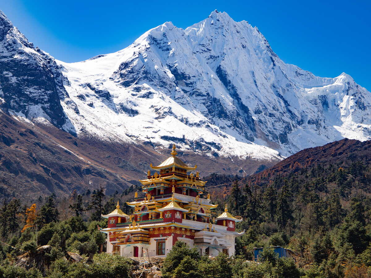Un temple coloré au premier plan avec des montagnes enneigées en arrière-plan.