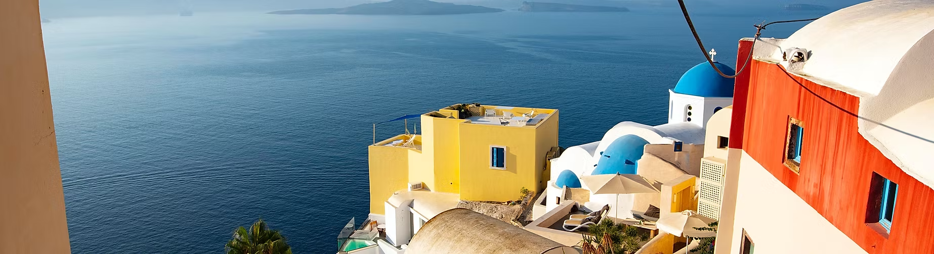 Vues des maisons traditionnelles à Santorin avec des murs colorés et des dômes bleus surplombant la mer Égée.