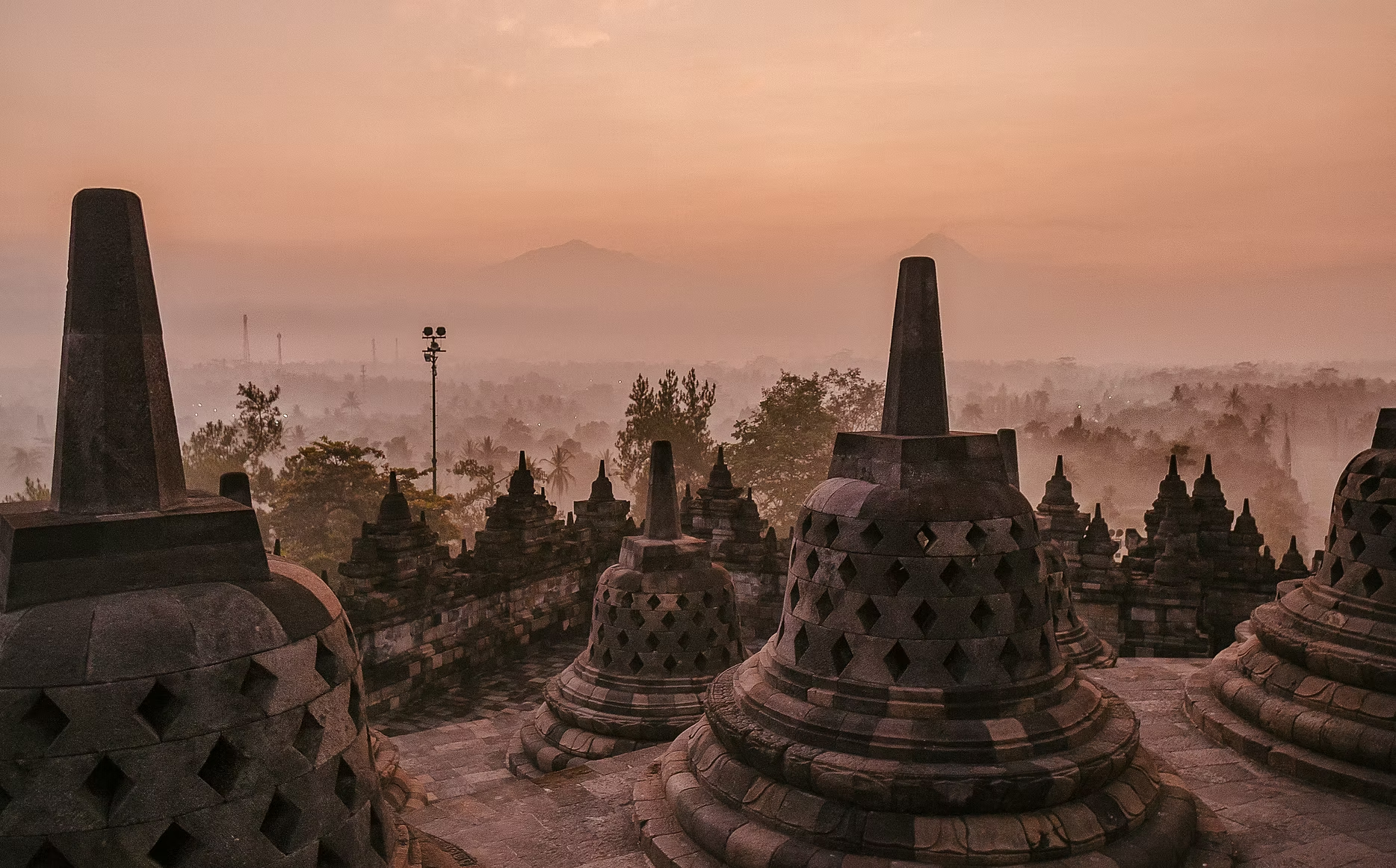 Vue sur la ville avec des temples en pierre, au lever ou coucher du soleil, avec des montagnes en arrière-plan