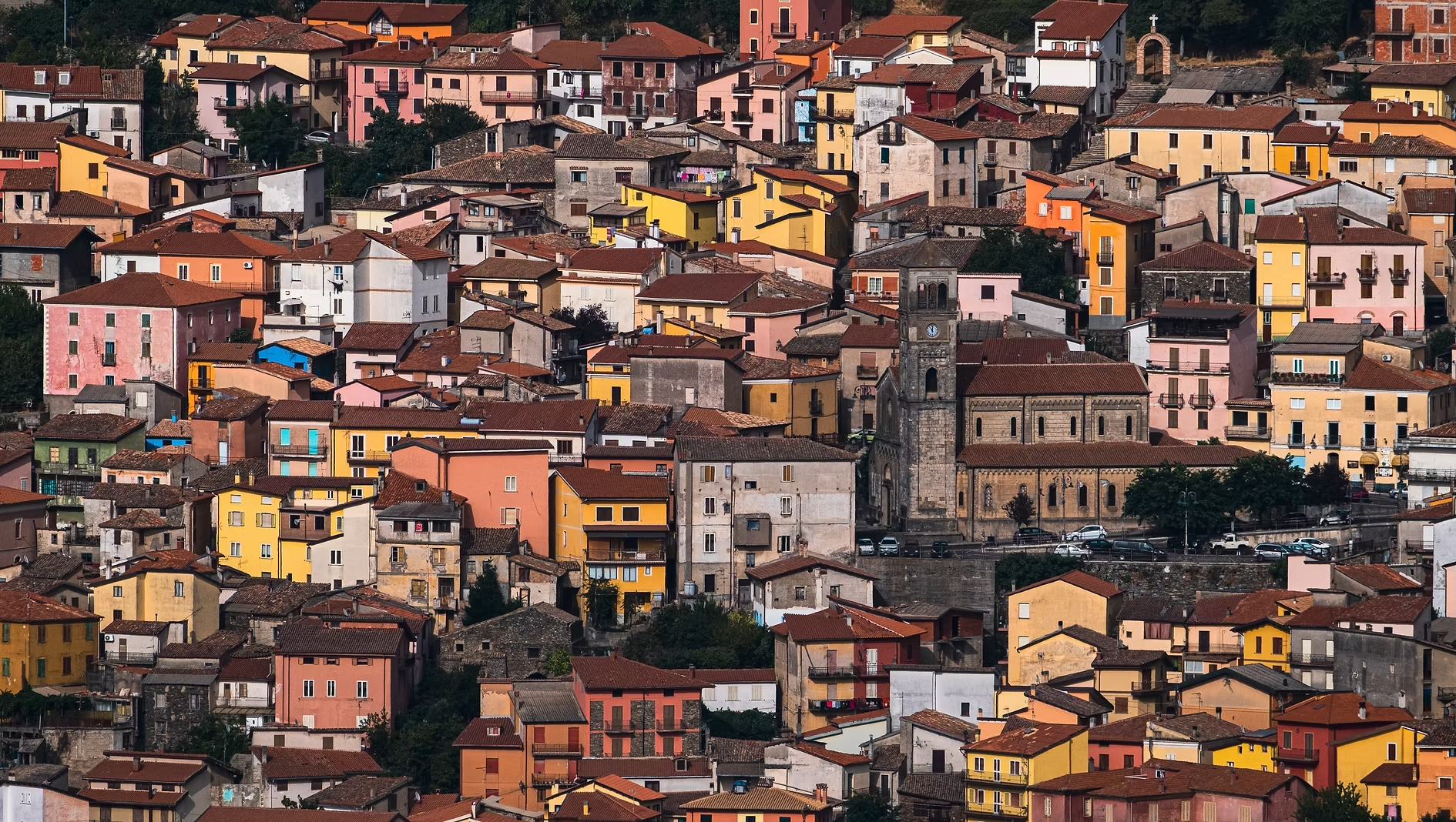 Vue d'une petite ville italienne avec des maisons colorées et un clocher d'église en pierre au centre.