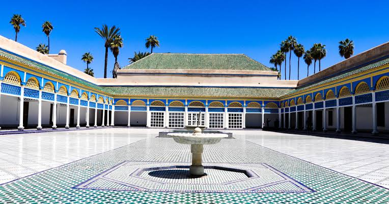 Centrale d'Alhambra avec un patio intérieur, fontaine, murs décorés, et palmiers en arrière-plan.
