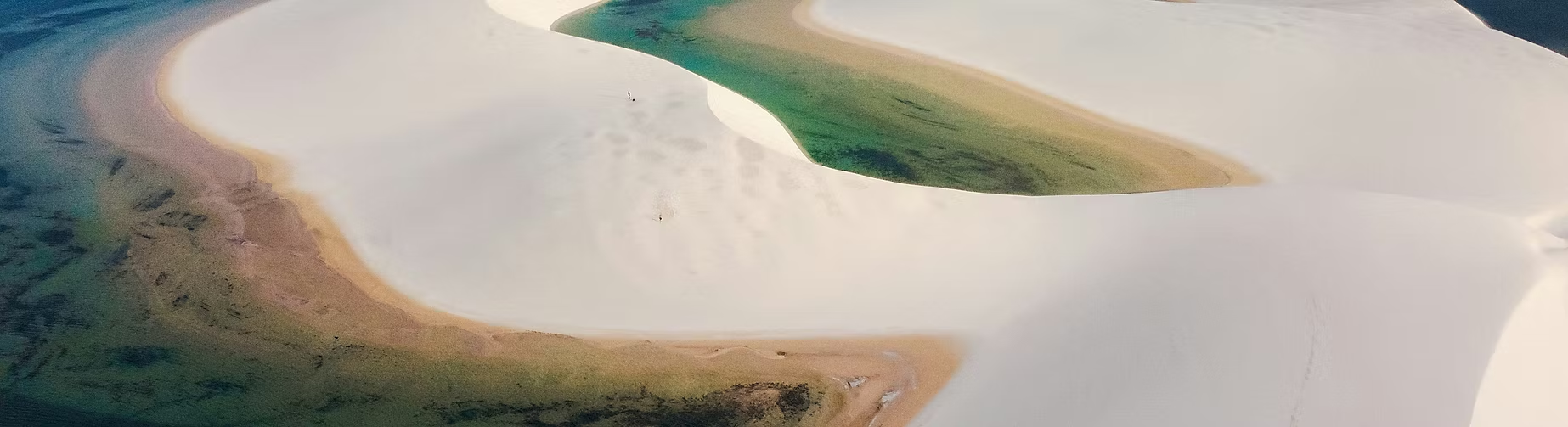 Vues aériennes de dunes de sable blanc avec des zones vertes calcaires, en forme de vagues ou de courbes, dans un paysage naturel désertique.