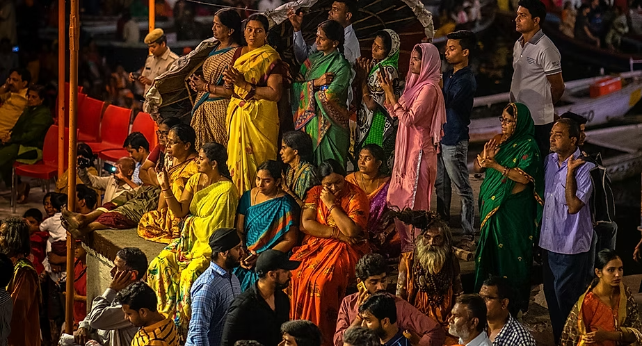 Groupe de personnes indiennes, principalement des femmes en sari colorés, assistant à un événement ou une célébration.