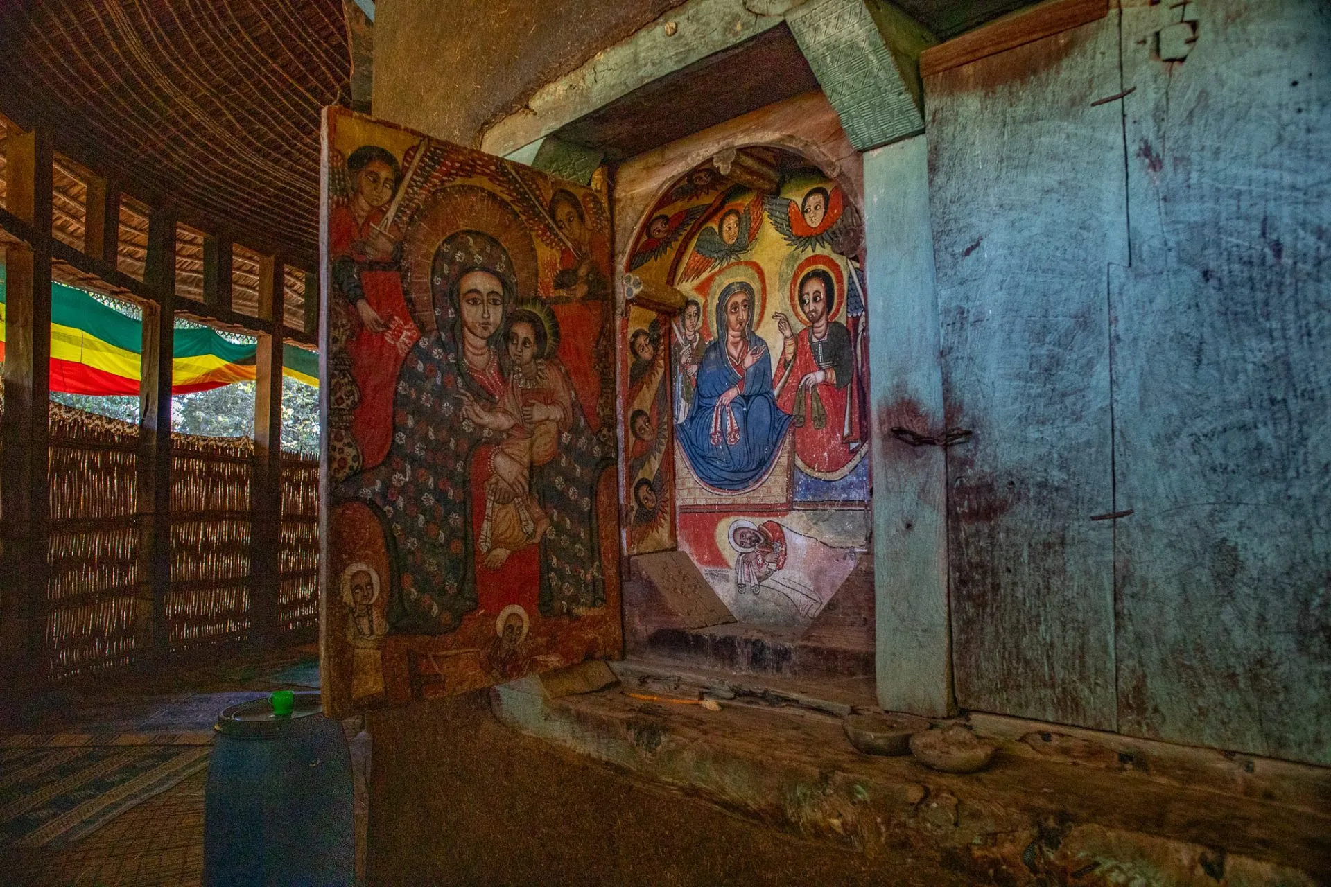 Peinture religieuse dans une église en bois représentant Marie avec l'enfant Jésus et des anges, décorée de couleurs vives.