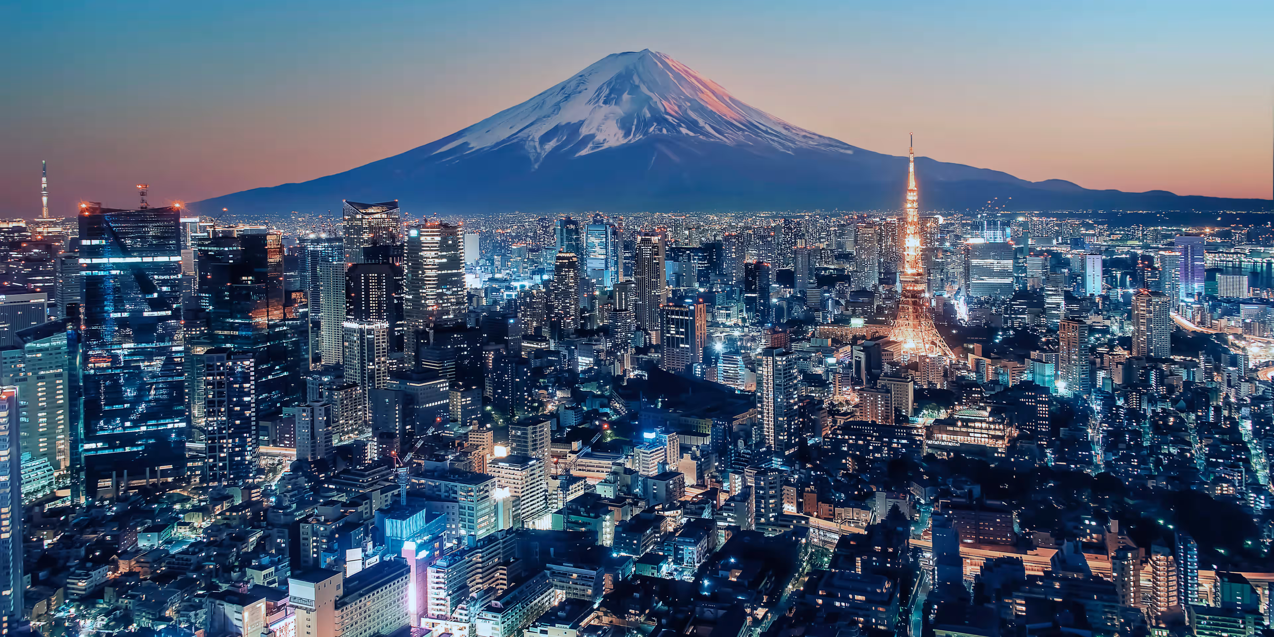 Une vue nocturne sur la ville de Tokyo avec le Mont Fuji en arrière-plan, illuminée par les lumières de la ville et la lueur du coucher de soleil sur la montagne.