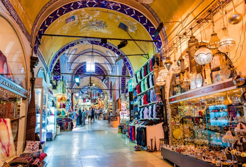Intérieur d'un marché couvert avec des vendeurs proposant des vêtements, des bijoux et des objets artisanaux dans un espace aux arches colorées.